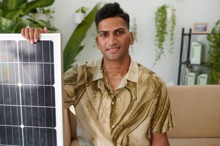 Téléchargez les photos : Portrait d'un Indien souriant montrant un panneau solaire qu'il a commandé pour son système - en image libre de droit