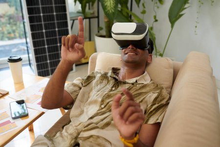 Téléchargez les photos : Homme souriant en réalité virtuelle casque regarder la vidéo sur l'installation du système solaire - en image libre de droit