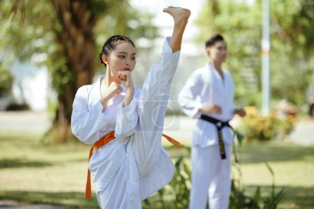 Téléchargez les photos : Athlète de taekwondo faisant coup de pied élevé lors de l'entraînement dans le parc - en image libre de droit