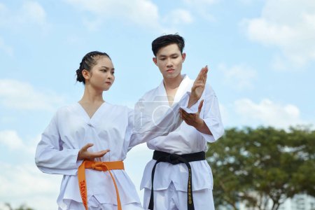 Téléchargez les photos : Instructeur de taekwondo expliquant fille comment garder les bras levés lors de la position - en image libre de droit