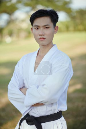 Portrait of serious confident taekwondo athlete wearing dobok with black belt