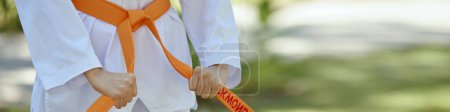 En-tête avec taekwondo athlète attachant ceinture orange