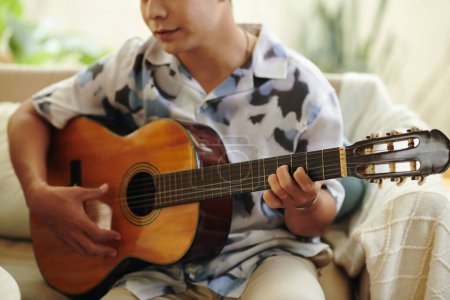 Téléchargez les photos : Image recadrée d'un homme créatif jouant de la guitare à la maison - en image libre de droit