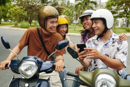Photo for Young people discussing map on smartphone when discussing where to ride motorbikes - Royalty Free Image