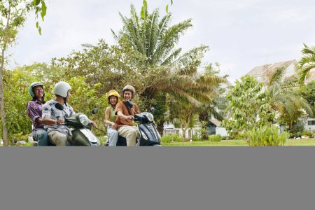 Photo for Two excited Vietnamese couples riding motorbikes - Royalty Free Image