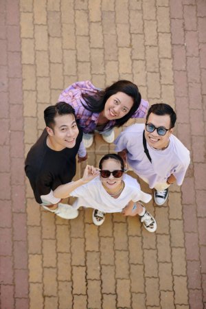 Téléchargez les photos : Des jeunes Vietnamiens souriants, hommes et femmes, debout en cercle et regardant la caméra - en image libre de droit