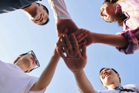 Photo for Group of friends stacking hands to express support and unity, view from below - Royalty Free Image