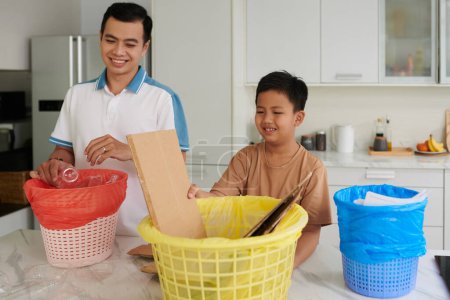 Foto de Orgulloso padre enseñando a su hijo a clasificar y categorizar basura - Imagen libre de derechos