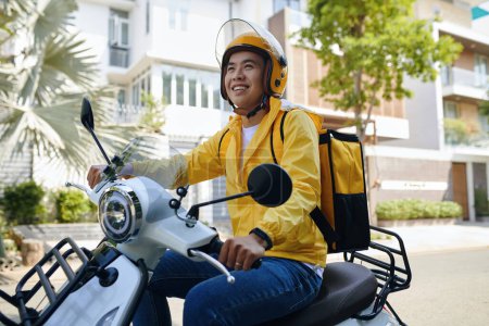 Téléchargez les photos : Courrier souriant en casque équitation moto - en image libre de droit
