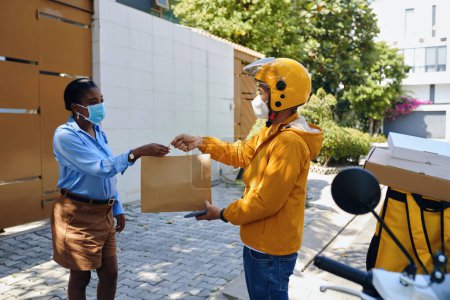 Téléchargez les photos : Femme en masque de protection demandant au messager de livrer le paquet - en image libre de droit