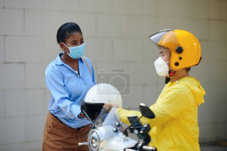 Téléchargez les photos : Sourire femme noire portant un casque avant de monter taxi moto - en image libre de droit