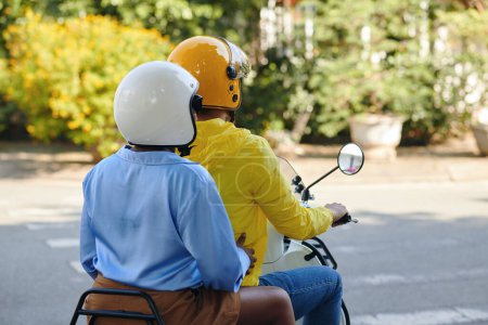 Photo for Motorbike taxi driver and passenger in helmets riding in city, view from the back - Royalty Free Image
