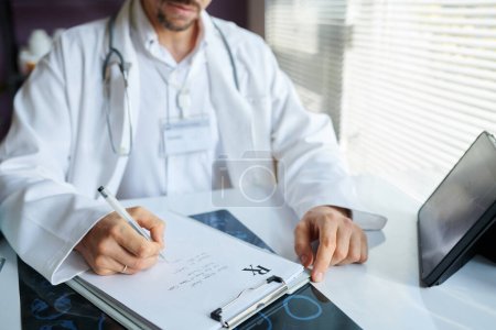 Photo for Hands of physician having online meeting with colleague when writing out prescription for patient - Royalty Free Image