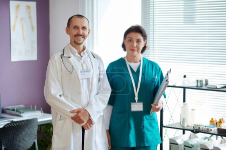 Foto de Retrato del médico general sonriente y la enfermera de pie en el consultorio médico - Imagen libre de derechos
