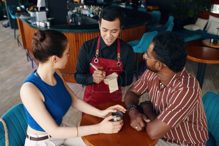 Téléchargez les photos : Serveur parler aux clients dans les restaurants lors de la rédaction de la commande - en image libre de droit