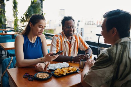 Téléchargez les photos : Groupe souriant d'amis se réunissant au café pour prendre un verre et parler - en image libre de droit