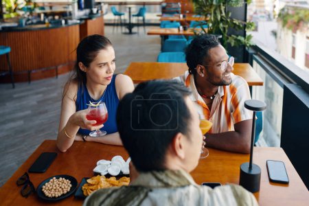 Téléchargez les photos : Groupe de touristes assis à la table du café et regardant à l'extérieur par une grande fenêtre - en image libre de droit