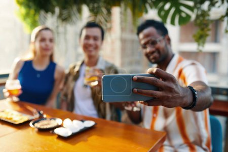 Téléchargez les photos : Homme se filmer passer du temps avec des amis dans le bar - en image libre de droit