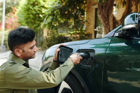 Téléchargez les photos : Indien propriétaire de voiture électrique recharge son véhicule - en image libre de droit