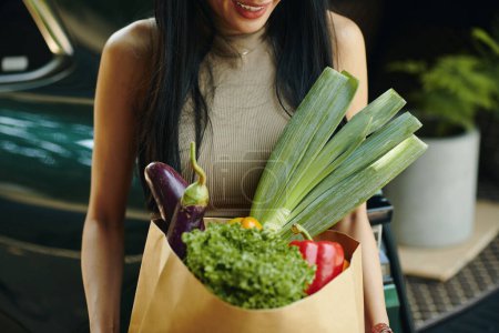 Photo for Cropped image of smiling woman holding bag of fresh groceries - Royalty Free Image