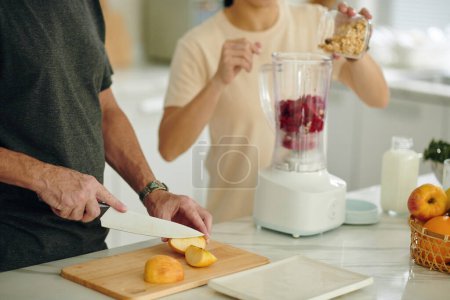 Foto de Hombre corte manzanas para el desayuno smoothie - Imagen libre de derechos