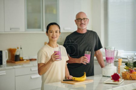 Foto de Sonriendo hombre y mujer maduros teniendo batido rosa para el desayuno - Imagen libre de derechos