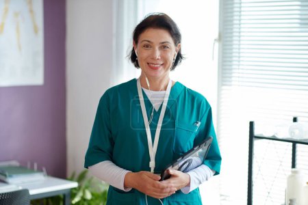 Foto de Smiling mature medical nurse in green scrubs - Imagen libre de derechos