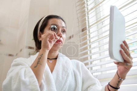 Téléchargez les photos : Femme utilisant l'outil de fronceur de cils avant d'appliquer le mascara - en image libre de droit