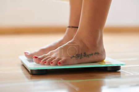 Cropped image of woman standing on scales, checking her weight
