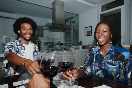 Téléchargez les photos : Amis souriants griller avec des verres de vin à la maison - en image libre de droit