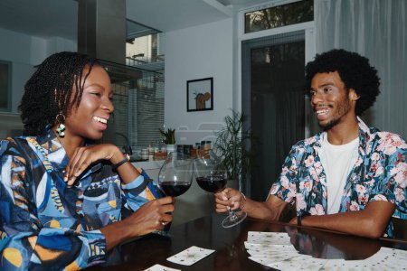 Photo for Happy Black couple spending evening at home drinking wine and doing tarot spread - Royalty Free Image