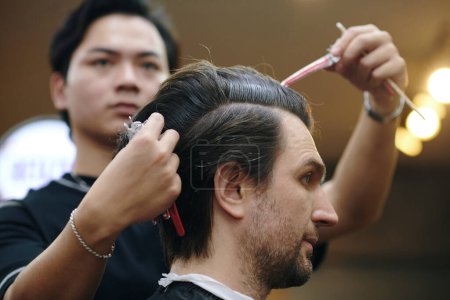 Friseur zieht Clips aus den Haaren des Kunden
