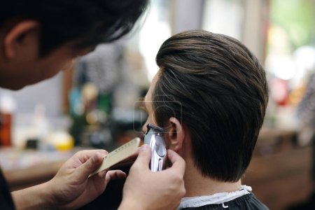 Barber combing and trimming sideburns hair of client