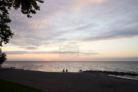Foto de A quiet beach at Madison township park. Madison is a small town in Ohio on Lake Erie. Two couples are walking the coastline. - Imagen libre de derechos