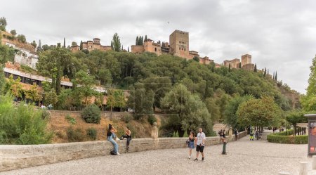 Téléchargez les photos : Alhambra Grenade Espagne - 09 14 2021 : Vue panoramique complète à la citadelle de l'Alhambra, du Paseo de los Tristes, promenade du triste (La Promenade de la Triste) avec des touristes visitant, Grenade, Espagne - en image libre de droit