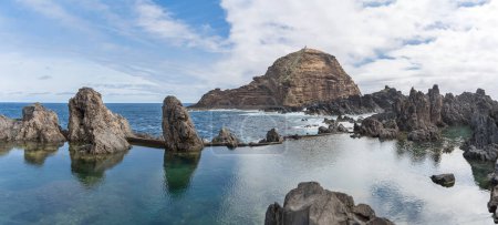 Téléchargez les photos : Île de Madère Portugal - 04 19 2023 : Vue panoramique des piscines naturelles sur le village de Porto Moniz, formé par des roches volcaniques, îlot de taupe en arrière-plan, côte de l'île de Madère, Portugal - en image libre de droit