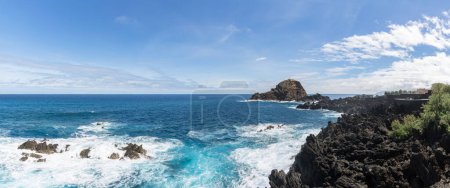 Foto de Isla de Madeira Portugal - 04 19 2023: Vista panorámica de las piscinas naturales en el pueblo de Porto Moniz, formado por rocas volcánicas, islote de Mole en el fondo, costa de la isla de Madeira, Portugal - Imagen libre de derechos