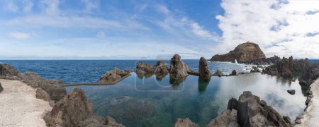 Foto de Isla de Madeira Portugal - 04 19 2023: Vista panorámica de las piscinas naturales en el pueblo de Porto Moniz, formado por rocas volcánicas, islote de Mole en el fondo, costa de la isla de Madeira, Portugal - Imagen libre de derechos