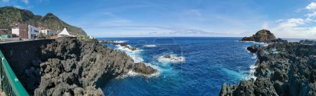 Photo for Madeira Island Portugal - 04 19 2023: Panoramic view of the natural pools on village of Porto Moniz, formed by volcanic rocks, village buildings in the background, coast of the Madeira island, Portugal - Royalty Free Image