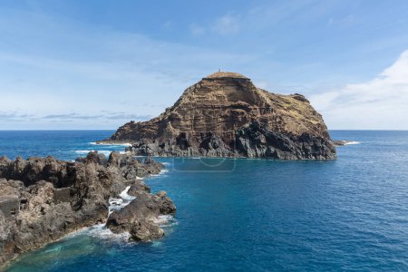Foto de Isla de Madeira Portugal - 04 19 2023: Vista al islote de Mole y rocas costeras, en el pueblo de Porto Moniz, formado por rocas volcánicas, costa de la isla de Madeira, Portugal - Imagen libre de derechos