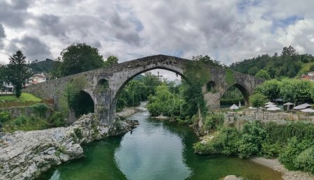 Photo for Leon Spain - 07 05 2021:Panoramic view at the Roman bridge over Sella river, an iconic bridge on Cangas de Onis downtown city, Picos de Europa or Peaks of Europe, Cantabrian Mountains, Spain - Royalty Free Image
