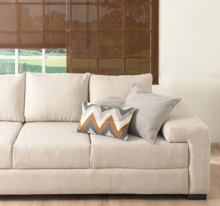 Téléchargez les photos : Un salon confortable avec un canapé beige moderne placé en face d'une fenêtre avec flux de lumière naturelle dans - en image libre de droit
