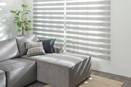 Téléchargez les photos : Un canapé moderne gris clair avec un repose-pieds assorti et un coussin décoratif, à l'intérieur d'un appartement moderne - en image libre de droit
