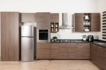 Foto de Un gabinete de cocina modular de diseño moderno, refrigerador de acero inoxidable con cajones y gabinetes de melamina marrón - Imagen libre de derechos