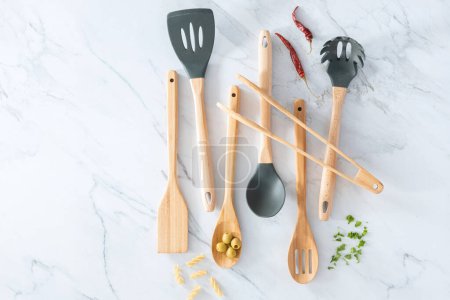 Photo for Wooden Kitchen Utensils Set on a marble countertop inside bright and modern kitchen - Royalty Free Image