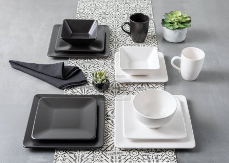 Ensemble de vaisselle en céramique noire et blanche sur fond gris.