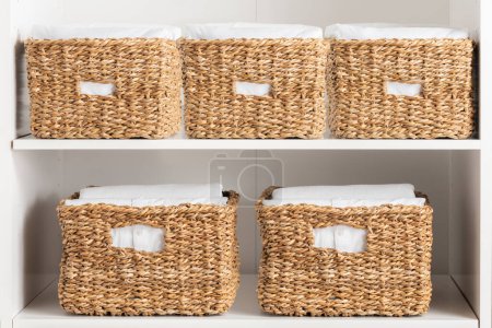 White shelves with wicker baskets for clothes and towels. Close-up