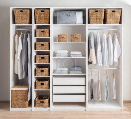 White wardrobe with wicker baskets, clothes and accessories. Modern interior design, Home closet organization