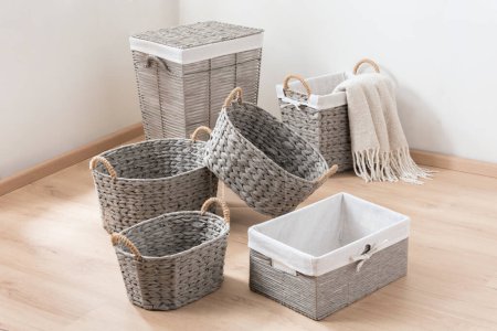 Photo for Empty gray wicker storage baskets set on wooden floor in a lighting interior room. Copy space - Royalty Free Image