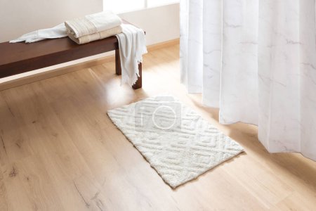Tapis de salle de bain blanc sur le sol dans le salon, concept de design d'intérieur moderne. Rideau de douche en marbre imprimé, sol en bois